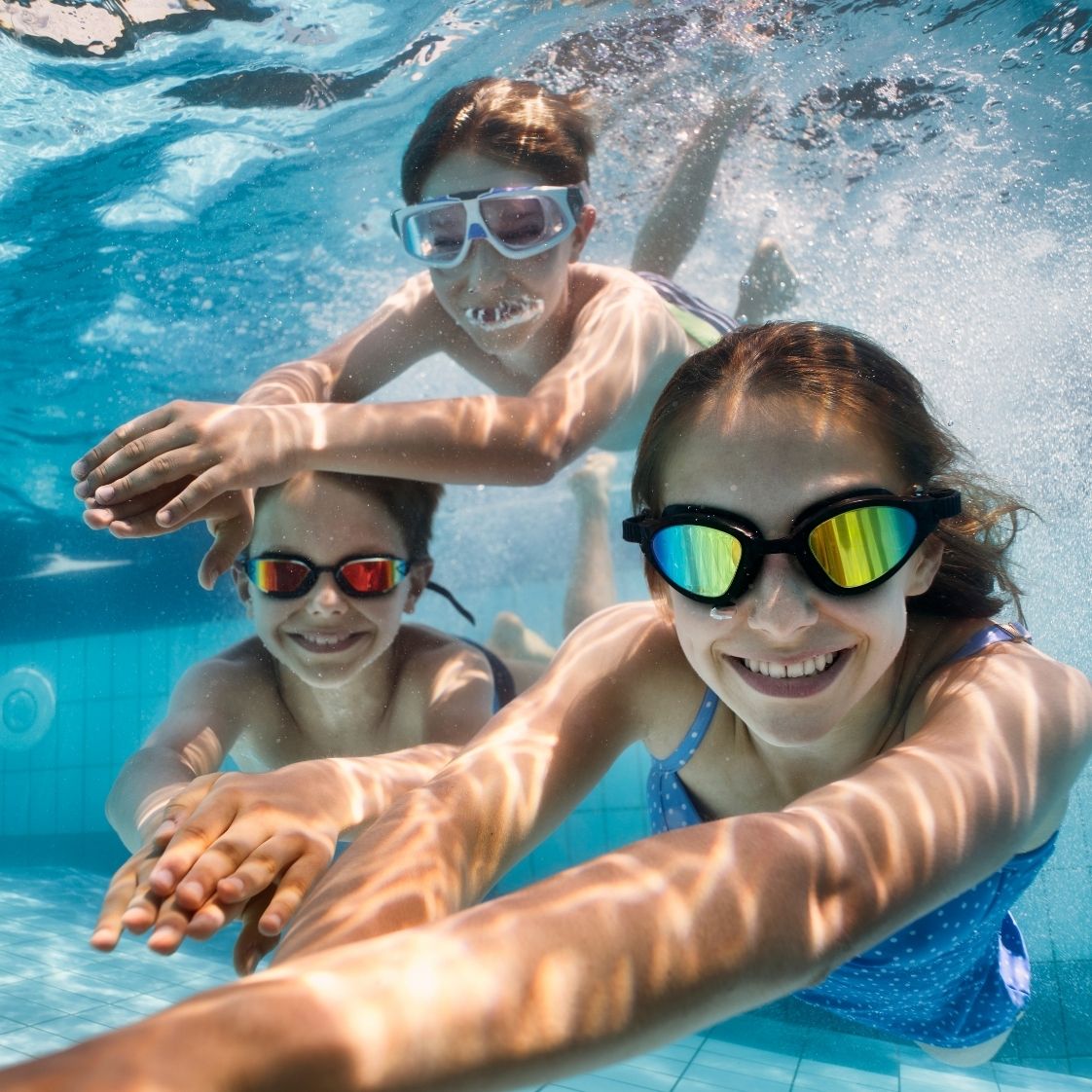 3 Kinder tauchen im Wasser mit Schwimmbrillen